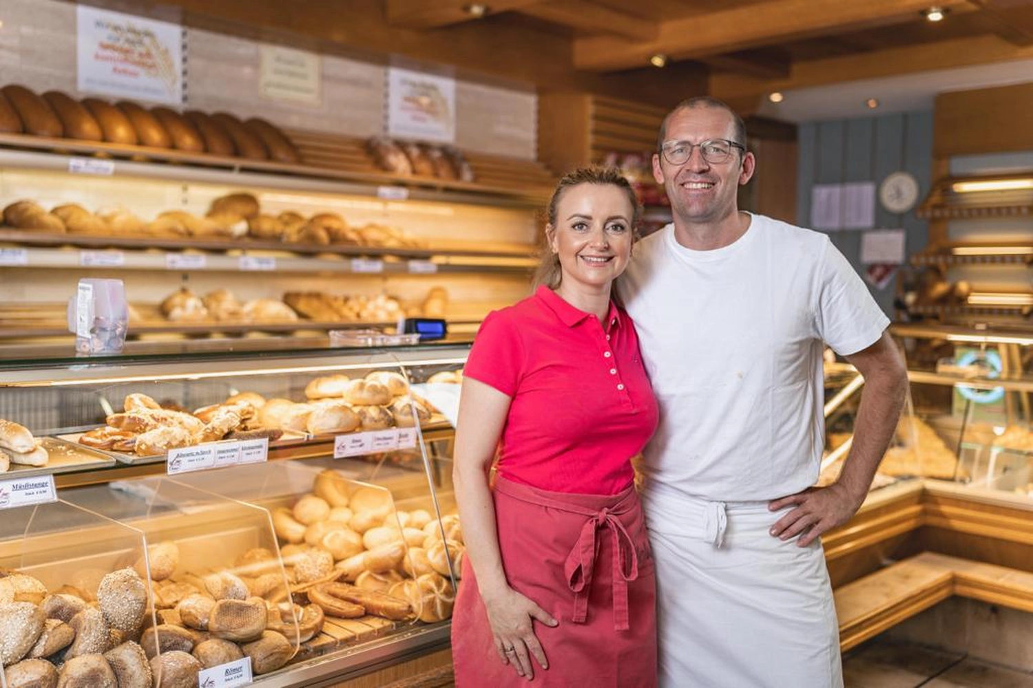 Bäckerei Konditorei Neher Rettenberg - Backwaren und Lebensmitteln - Ein Paar steht hinter dem Tresen einer traditionellen deutschen Bäckerei und präsentiert eine große Auswahl an frisch gebackenen Waren.